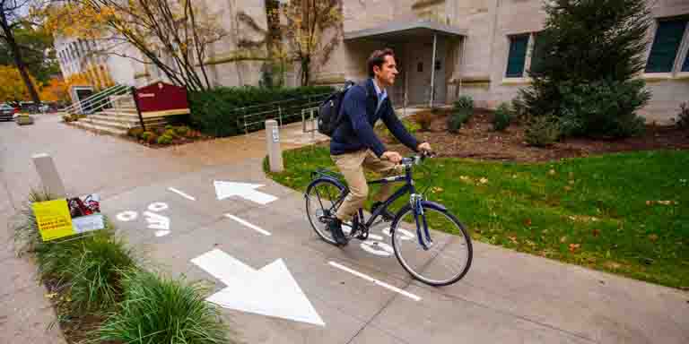 A person rides a bike on the 91ѰػƬ campus.